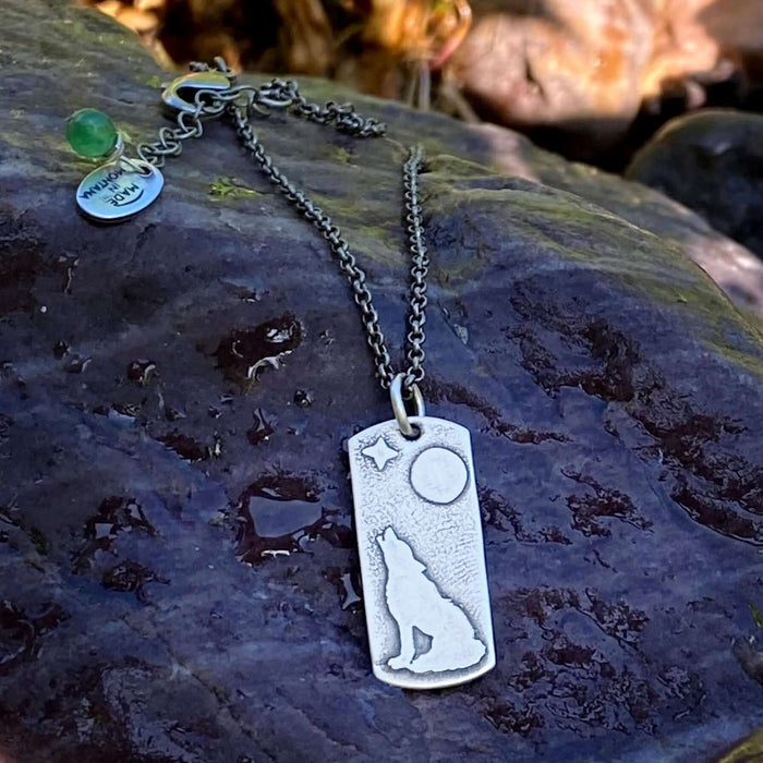 Howl Necklace featuring a wolf, moon, and star design on an adjustable rolo chain resting on a rock.