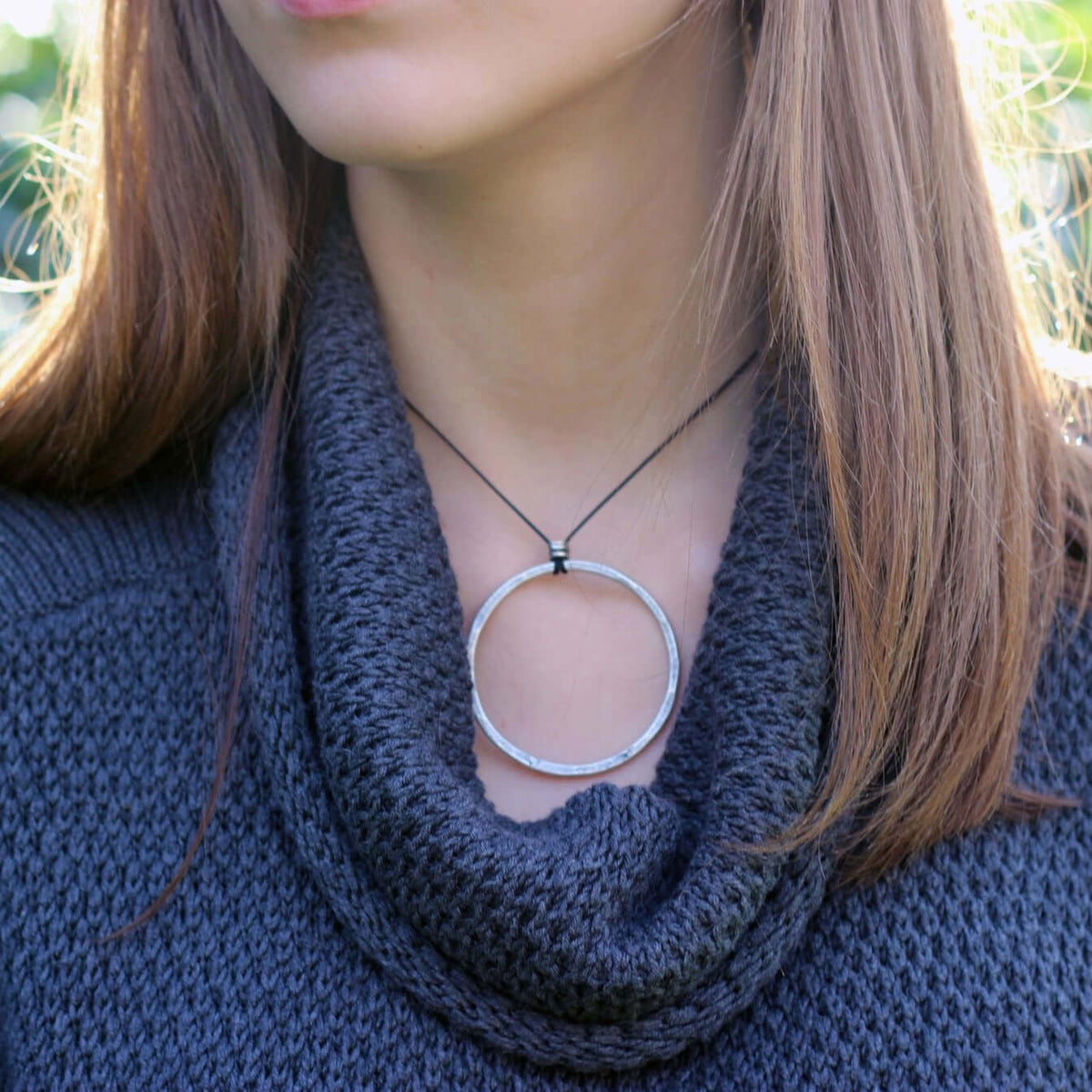 Model wearing a Hula Necklace with a raw brass and sterling silver finish, featuring a large circle design.
