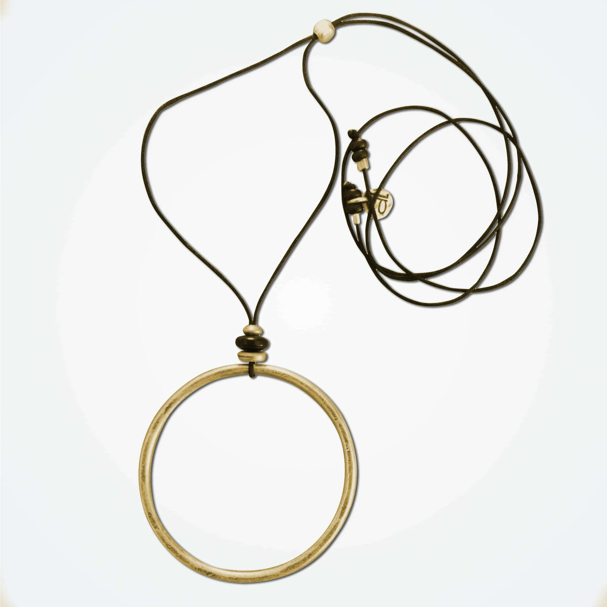 Hula Necklace featuring a raw brass circle hoop with sterling silver coating on adjustable cord.