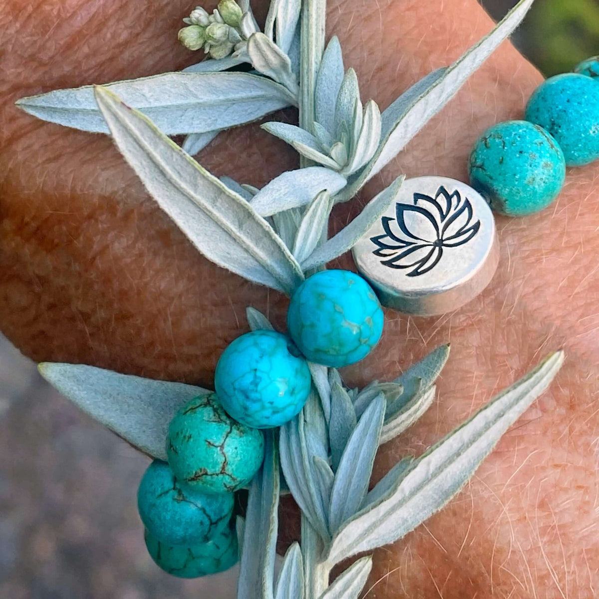 Lotus Stretch Bracelet - Gemstone Beaded Stretchy Bracelet showcasing turquoise beads and lotus emblem on a wrist.
