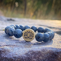 Lotus Stretch Bracelet - Gemstone Beaded Stretchy Bracelet with blue beads and lotus charm on a natural stone surface.