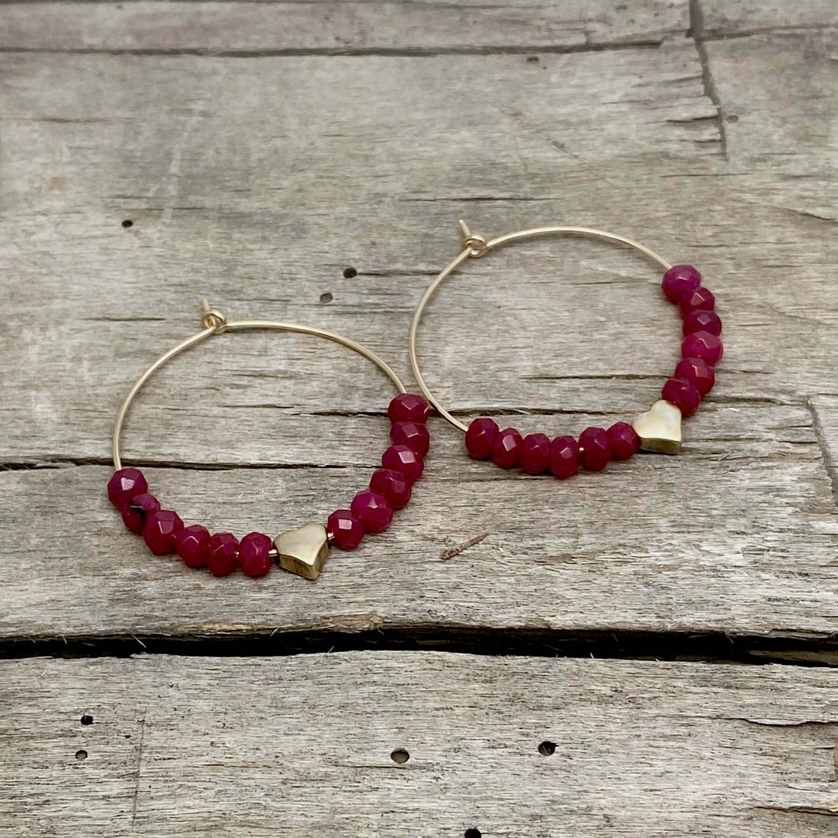 Love Earrings - Beaded hoop earrings with heart and ruby jade on wooden background.