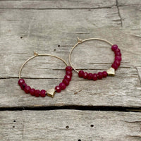 Love Earrings - Beaded hoop earrings with heart and ruby jade on wooden background.