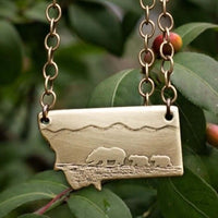 Mama and Cubs Necklace featuring a mother grizzly bear and her cubs, crafted from raw brass with detailed etching.
