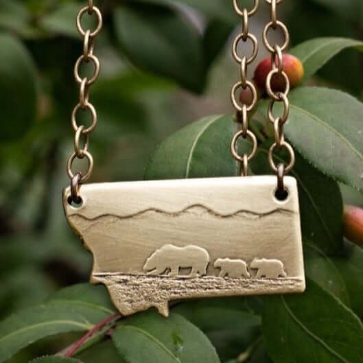 Mama and Cubs Necklace featuring a mother grizzly bear and her cubs, crafted from raw brass with detailed etching.