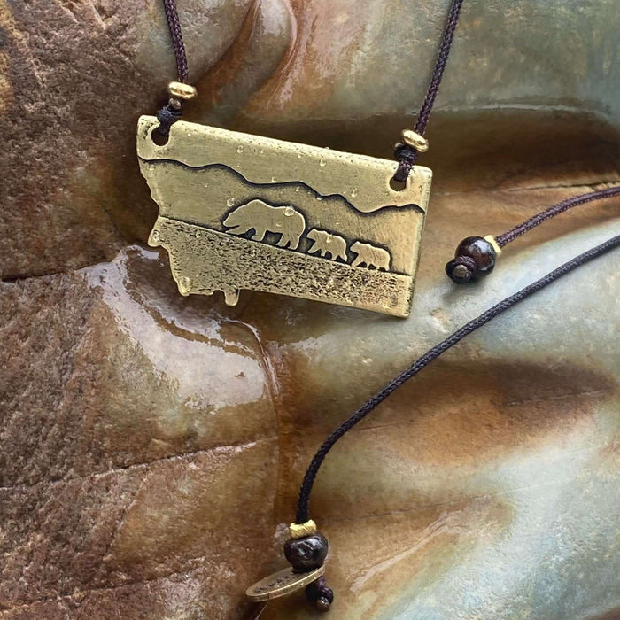 Mama and Cubs Necklace featuring a mother grizzly bear and her cubs, crafted in raw brass on an adjustable cord.