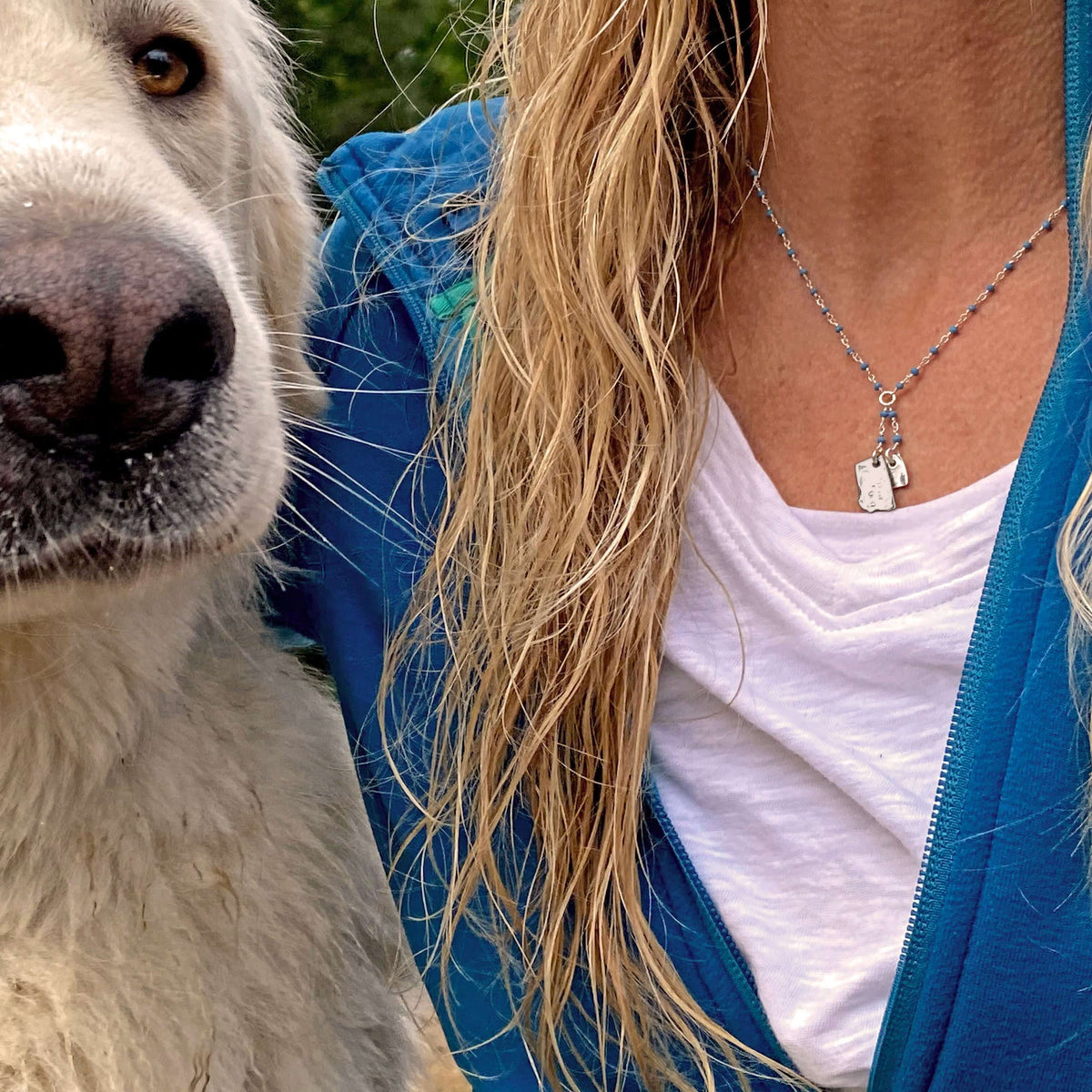 Montana Lariat Necklace worn by a woman next to a dog, featuring Montana outline and heart on a turquoise chain.