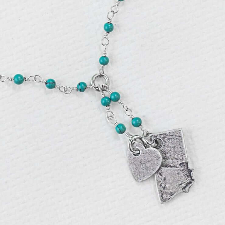 Montana Lariat Necklace featuring turquoise beads, heart charm, and Montana state outline in matte silver finish.