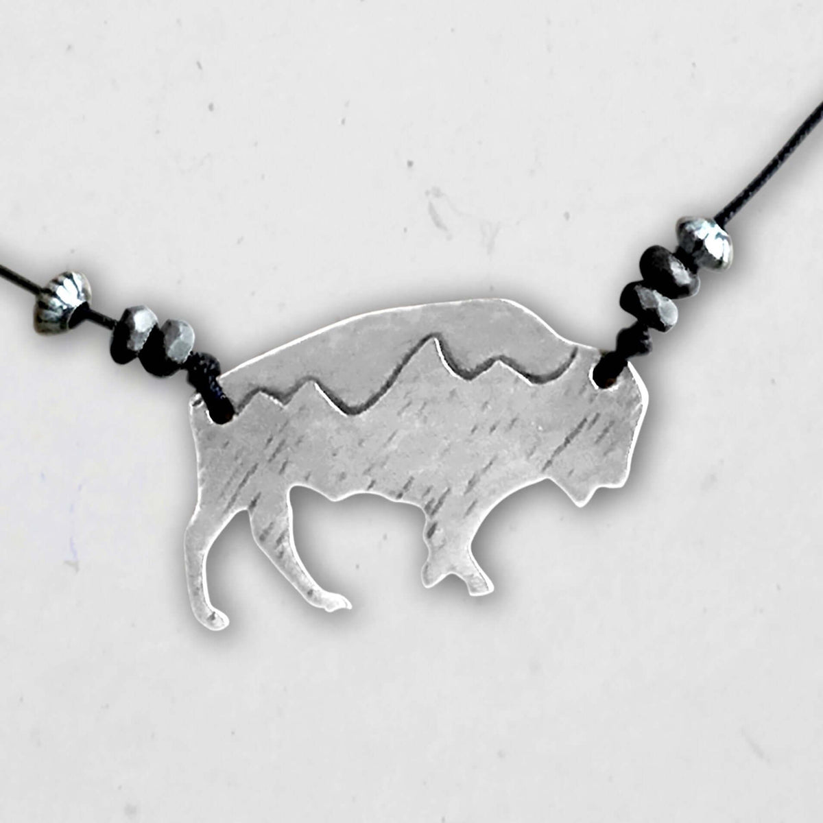 Mountains on Buffalo Necklace featuring a silver bison charm with mountain peaks and decorative beads.