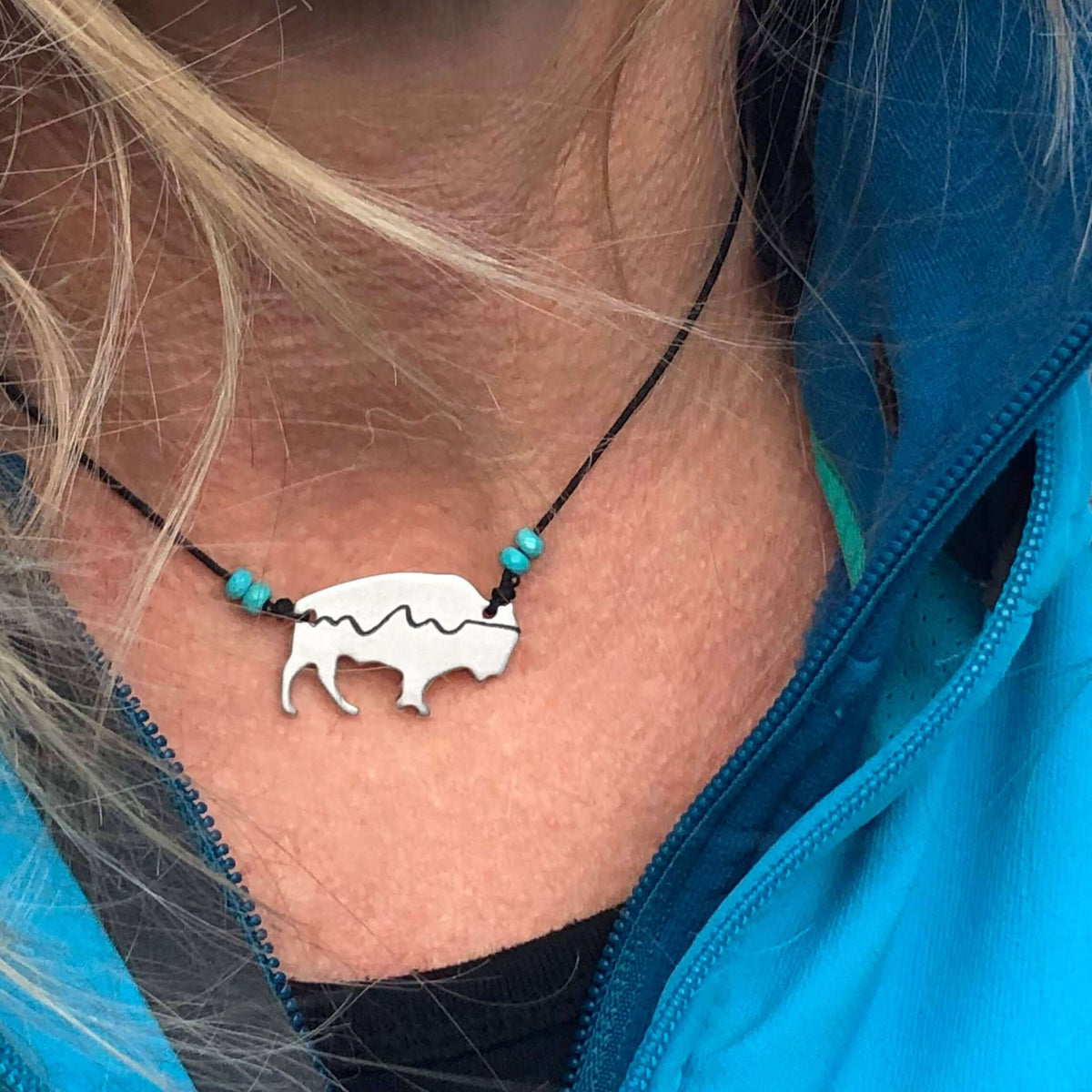Mountains on Buffalo Necklace with bison silhouette and turquoise beads worn by a person.