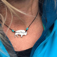 Mountains on Buffalo Necklace with bison silhouette and turquoise beads worn by a person.