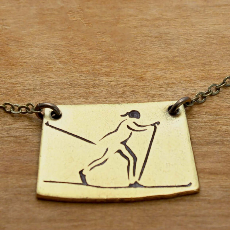 Nordic Run Necklace featuring an etched skier design, perfect for winter sports enthusiasts.
