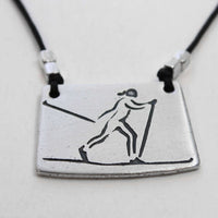 Nordic Run Necklace featuring a skier etched on a silver pendant with a black cord.