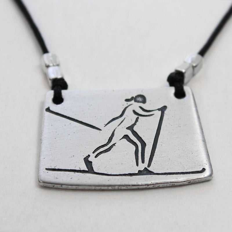 Nordic Run Necklace featuring a skier etched on a silver pendant with a black cord.