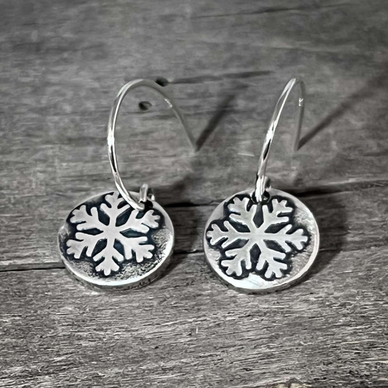 Powder Snowflake Earrings in silver with etched snowflake design on 0.45" disc, hanging from sterling silver earwires.