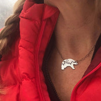 Poya Bear Necklace worn on a model featuring a bear silhouette with tree line in matte silver finish.