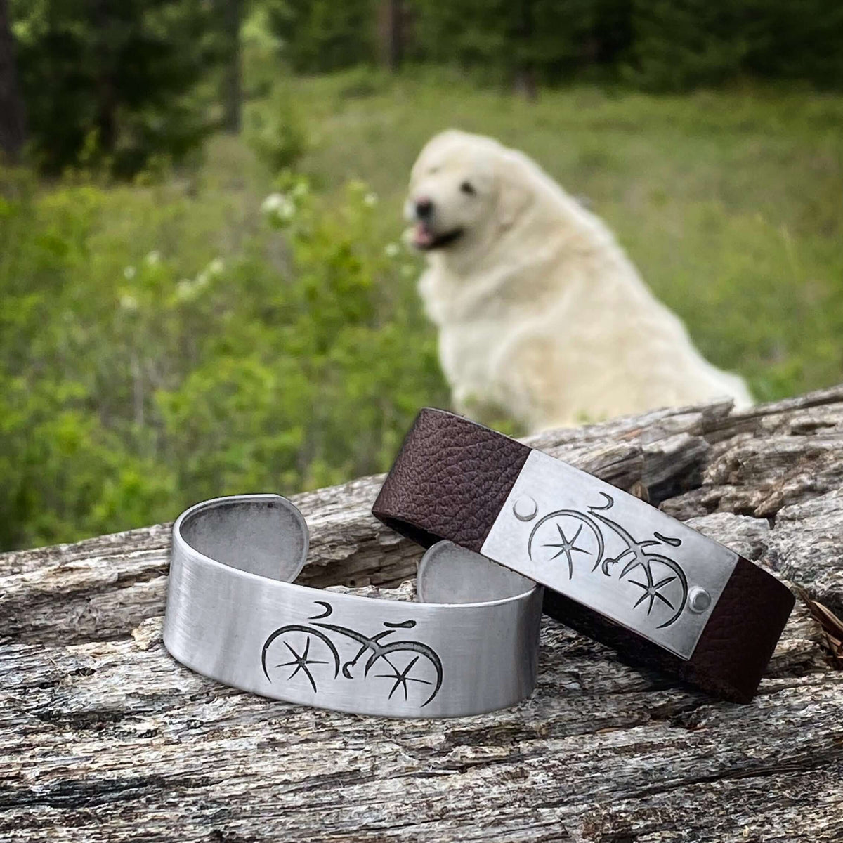 Ride Bicycle Cuff Bracelet displayed on a log in a natural setting with a dog in the background.