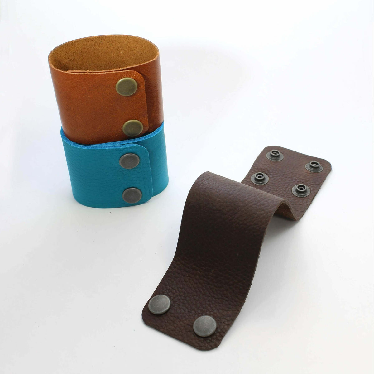 Rising Wolf Disk Leather Cuff in Espresso, Montana Whiskey and Creek Water shades, showcasing genuine leather design.