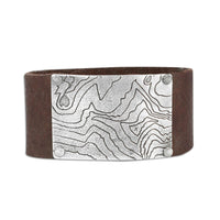 Rising Wolf Leather Cuff Bracelet featuring a topographic map design on a brown leather cuff.