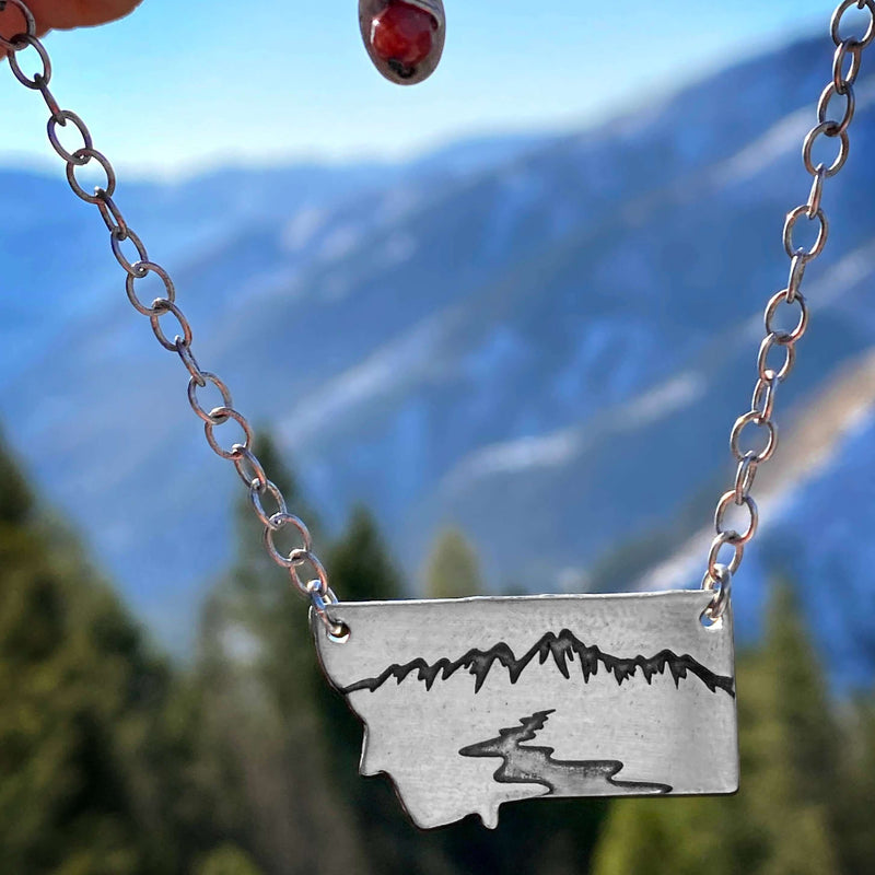 River Run Necklace featuring Montana outline, a mountain peak, and winding river, perfect for outdoor adventures.