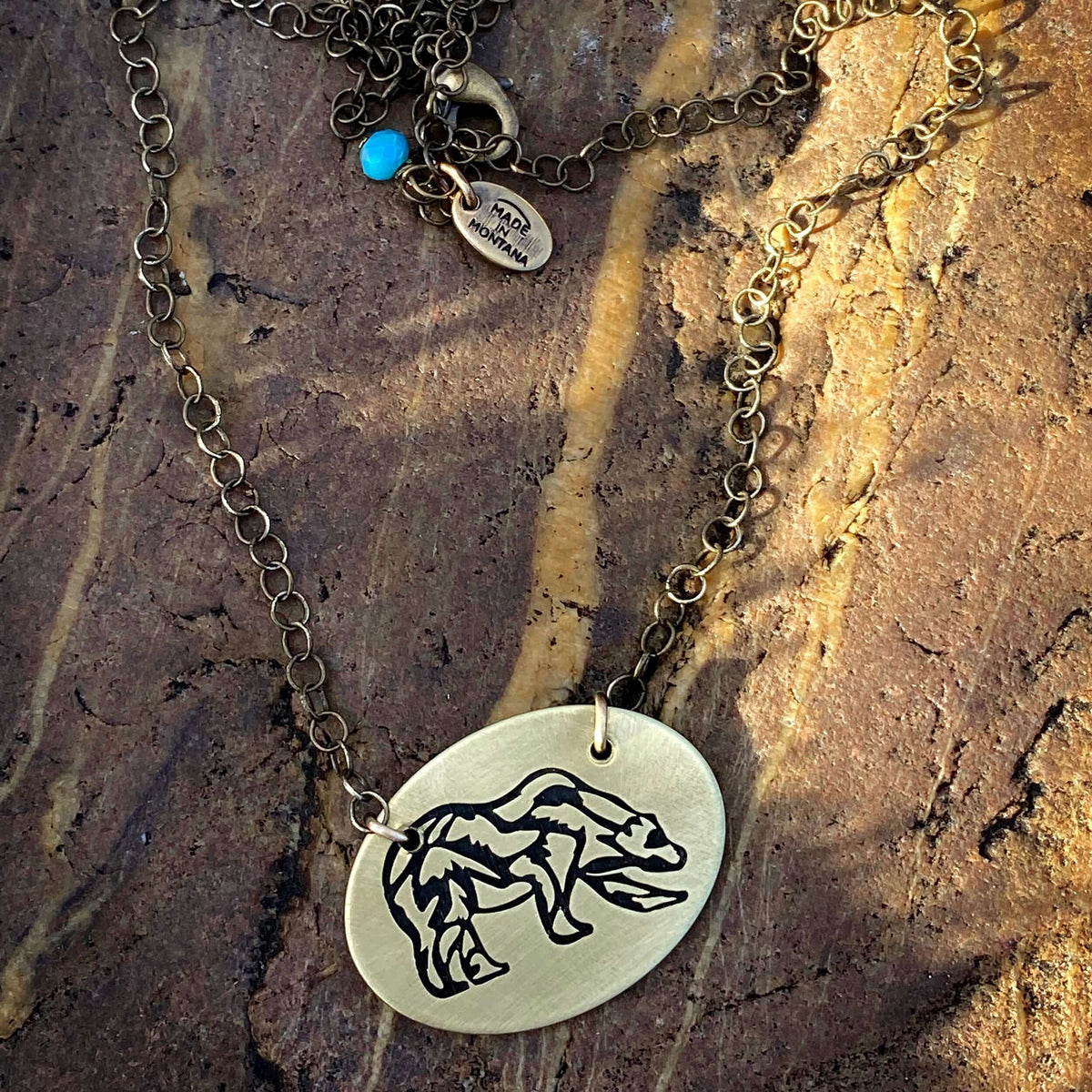 Rocky Bear Necklace featuring a grizzly bear pendant on a bronze chain, perfect for lovers of nature and adventure.