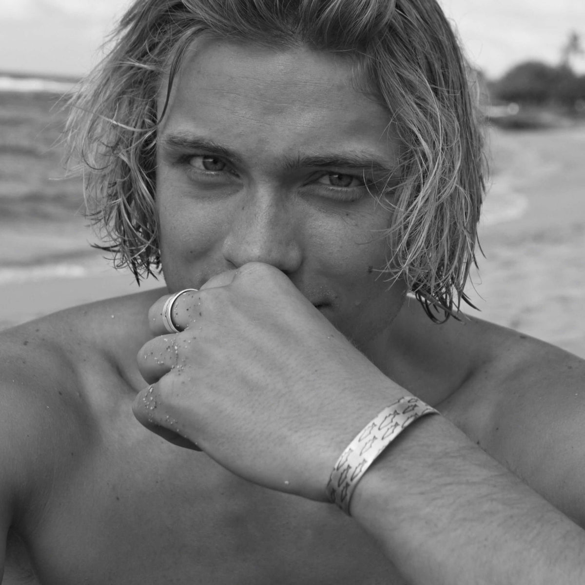 Close-up of a man wearing a Salmon Run Cuff Bracelet at the beach, showcasing its unique design and craftsmanship.