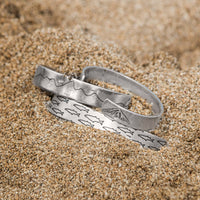 Salmon Run Cuff Bracelet showcasing unique designs on sandy background, ideal for nature lovers.