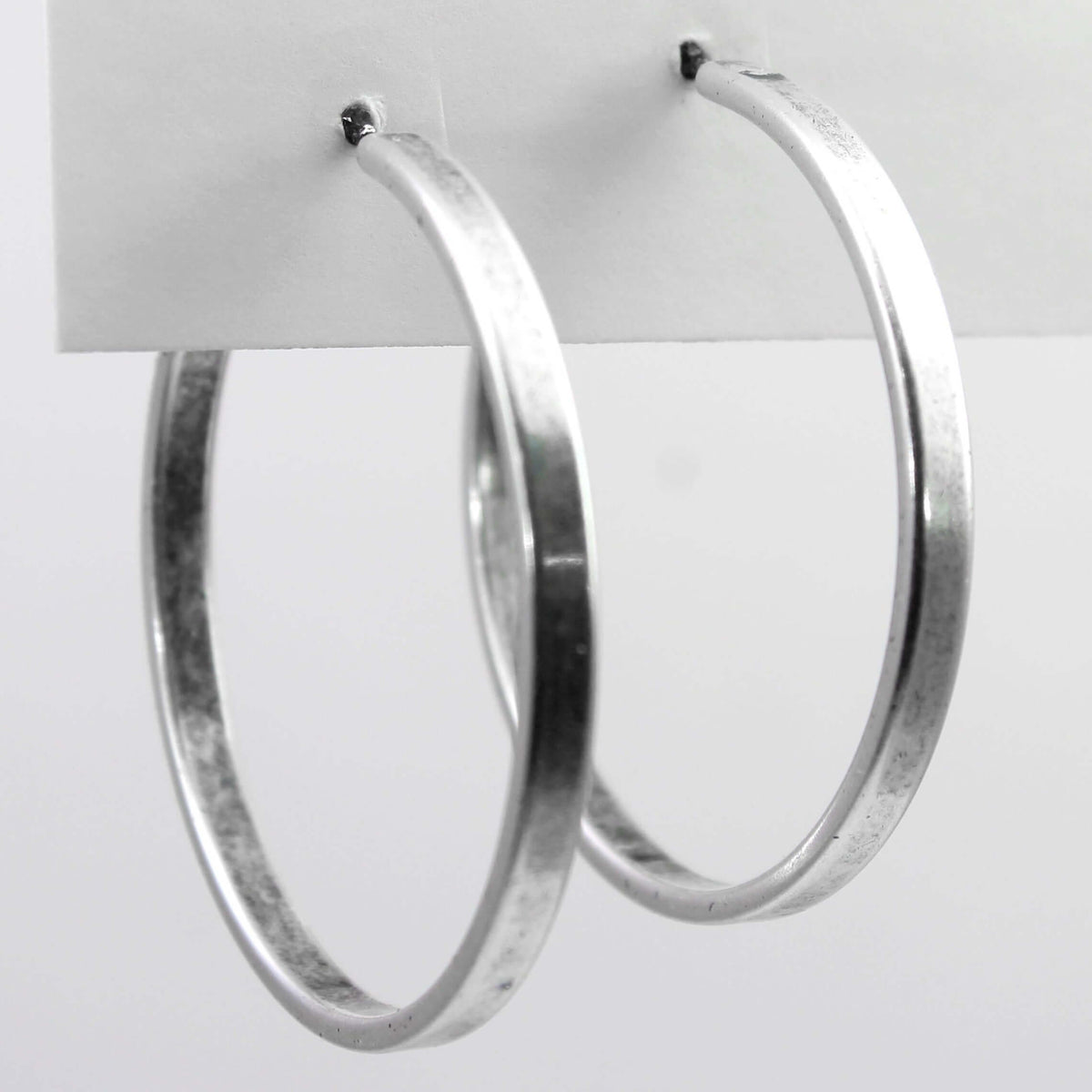 Simple Hoop Earrings displayed on a card, showcasing smooth silver finish and 1.5 inch diameter.