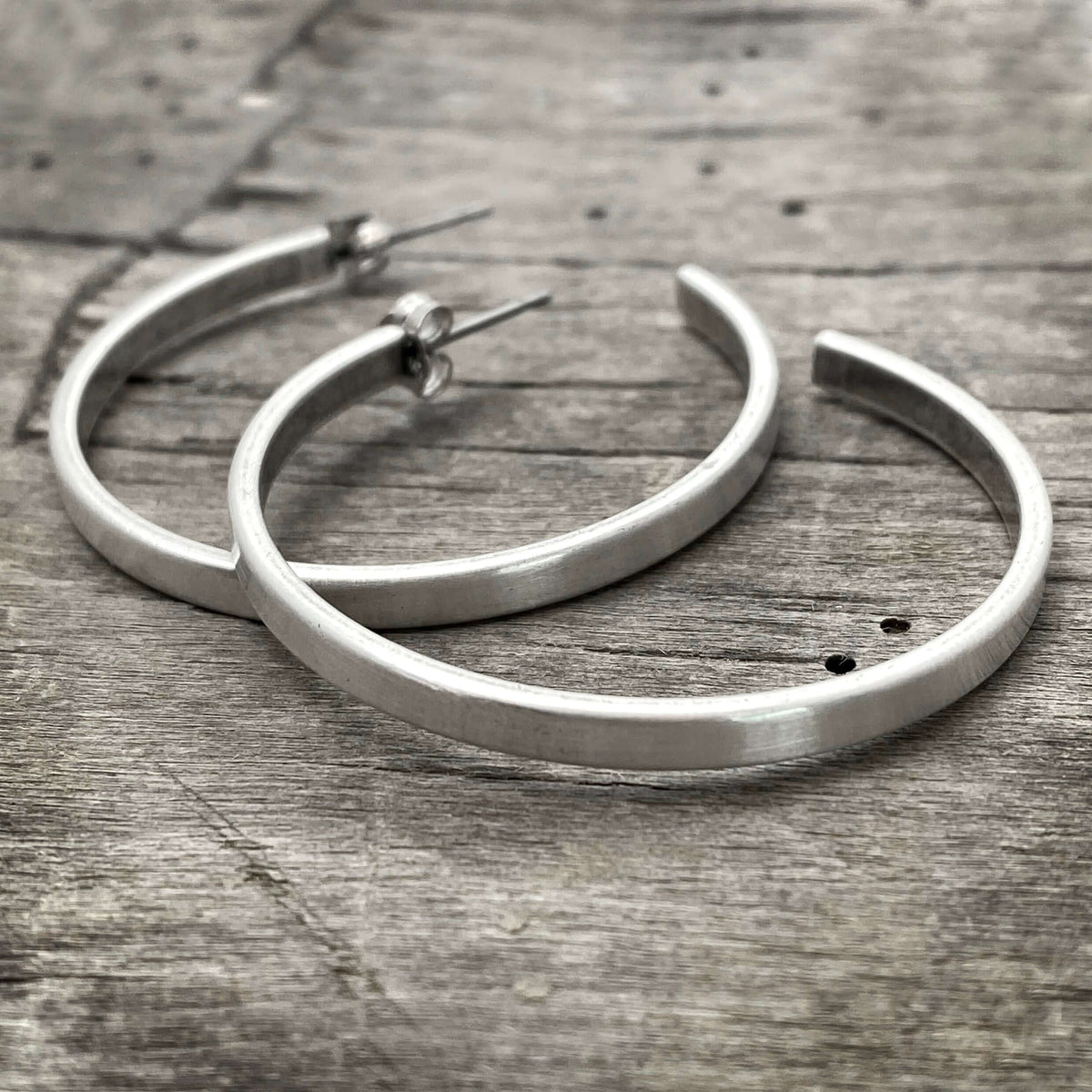 Simple Hoop Earrings - chic hammered silver hoops on wooden background.