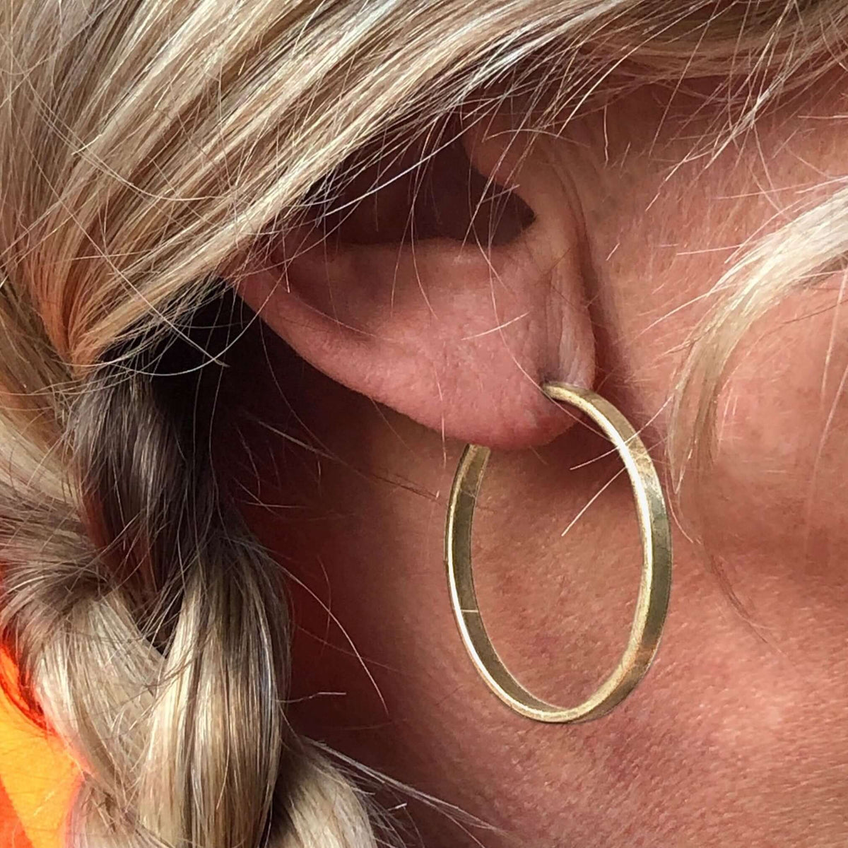 Simple Hoop Earrings showcased on a model's ear, highlighting the chic brass design and hammered texture.
