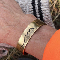 Simple Tetons Cuff Bracelet worn on wrist, featuring deep etched mountain design, perfect for nature lovers.