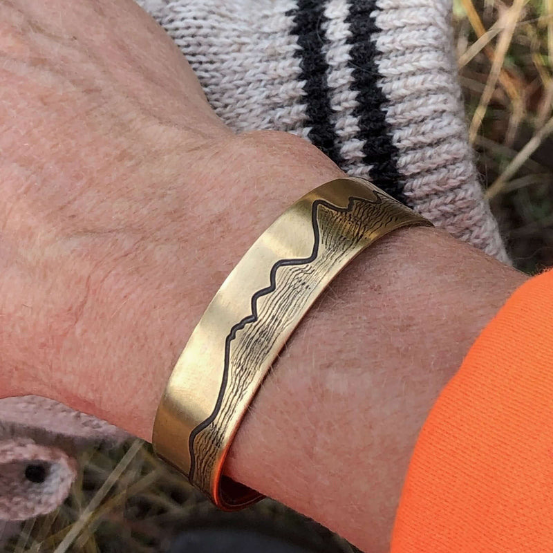 Simple Tetons Cuff Bracelet worn on wrist, featuring deep etched mountain design, perfect for nature lovers.