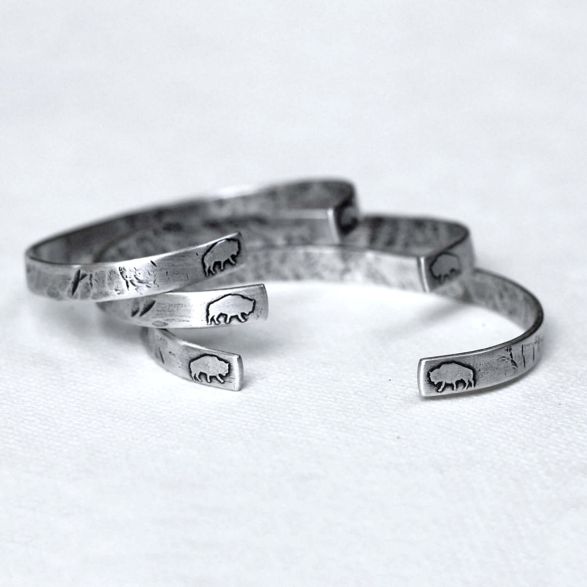 Skinny Buff Cuff Bracelet showcasing multiple raw brass designs etched with bison motifs.