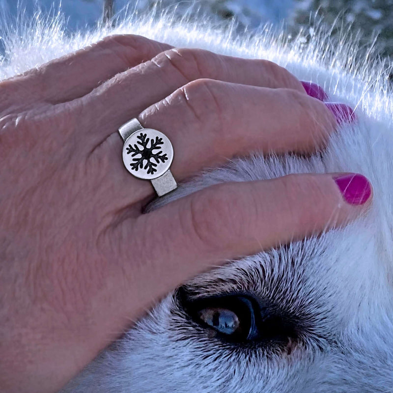 Snowflake Adjustable Ring showcased on a hand, highlighting its unique snowflake design against a snowy backdrop.