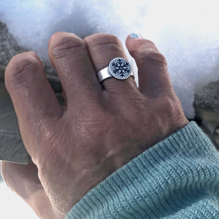 Snowflake Adjustable Ring on a hand, showcasing its charm and winter theme against a snowy background.