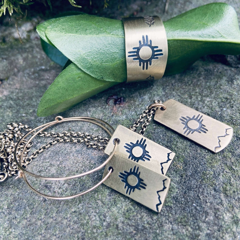 Sol Adjustable Ring and matching jewelry with Zia sun design on a natural setting.