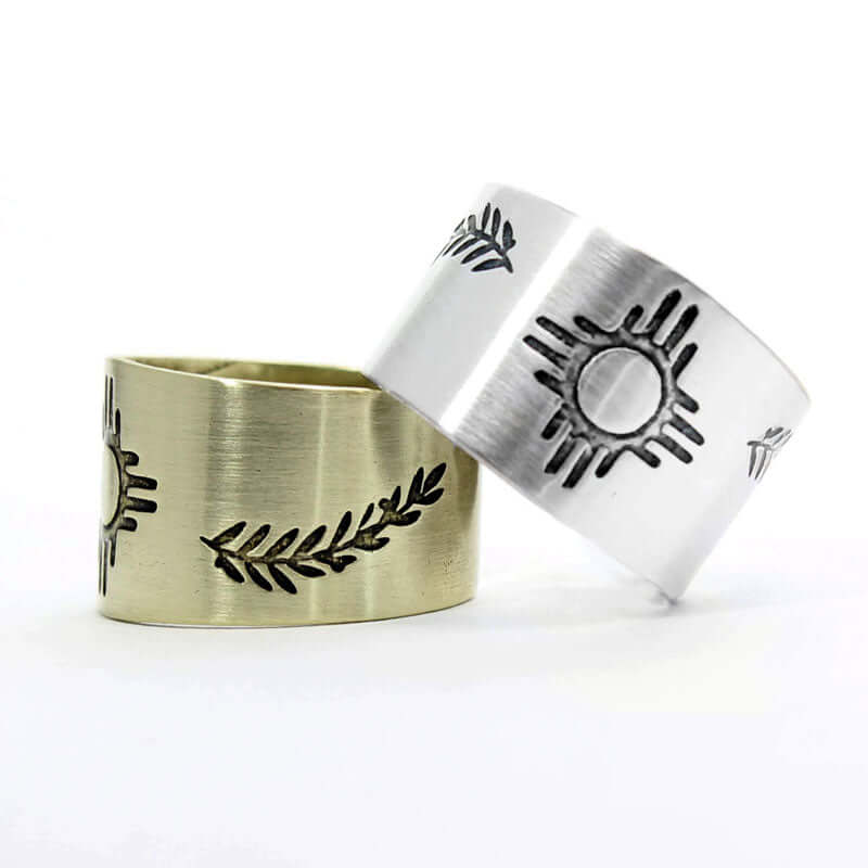 Sol Adjustable Ring showcasing two finishes, raw brass and silver, with unique Zia sun design and leaf detail.