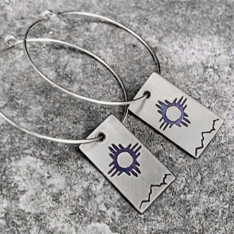 Sol Hoop Earrings featuring a Zia sun design crafted with raw brass and silver hoop earwires.