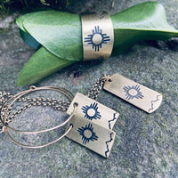 Sol Necklace featuring iconic Zia sun design etched on raw brass with accompanying accessories.
