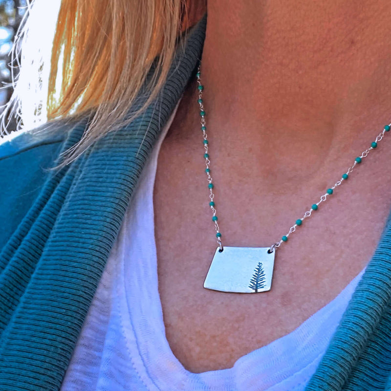 Spruce Necklace featuring a fern pendant on an adjustable beaded chain, perfect for nature lovers.