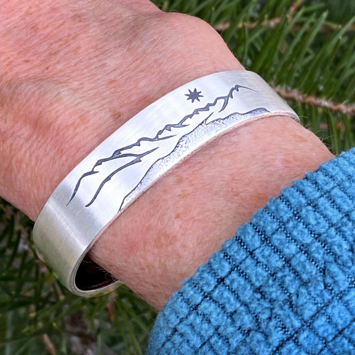 St. Mary Cuff Bracelet showcasing a nature-inspired design with mountain and star detailing on a silver cuff.