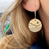 St. Mary Lake Earrings - Glacier Mountain and Lake with Sun shown on a model's ear with long blonde hair.