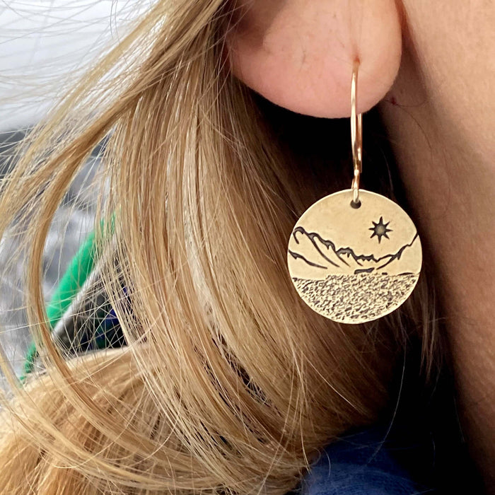 St. Mary Lake Earrings - Glacier Mountain and Lake with Sun shown on a model's ear with long blonde hair.