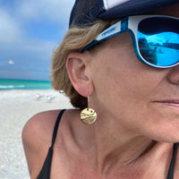 St. Mary Lake Earrings - Glacier Mountain and Lake with Sun worn by a woman at the beach, showcasing the design and colors.