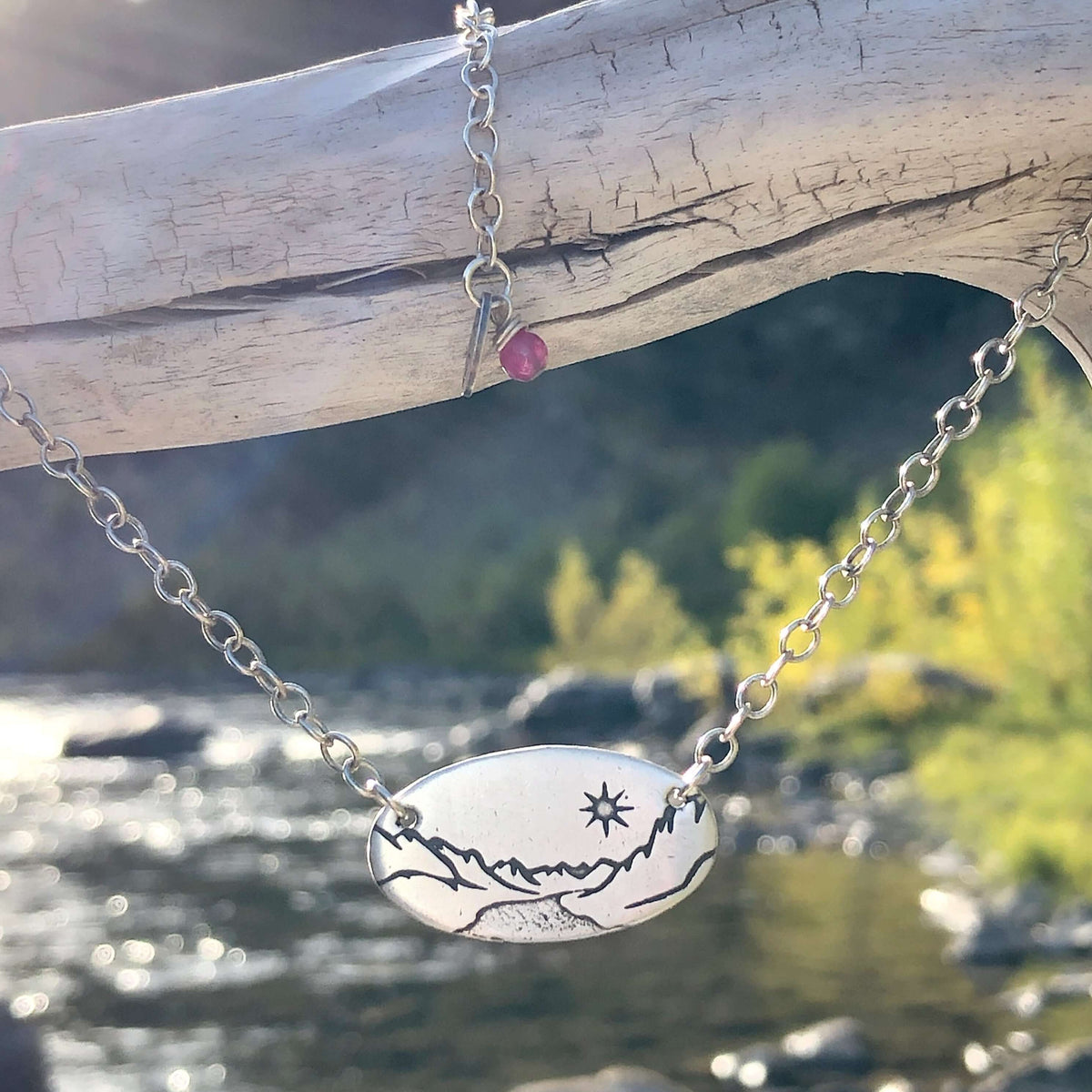 St. Mary Lake in Glacier Necklace featuring intricate etching with a simple cable chain, set against a natural background.