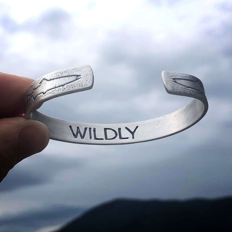 Trout on Tips Cuff Bracelet showcasing the word 'WILDLY' with a natural background.