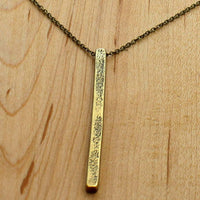 Twig Long Layered Necklace on a wooden background, showcasing its elegant gold twig design and adjustable cable chain.
