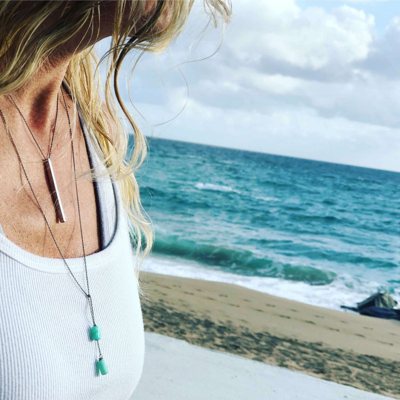 Twig Long Layered Necklace worn by a woman at the beach with ocean waves in the background.