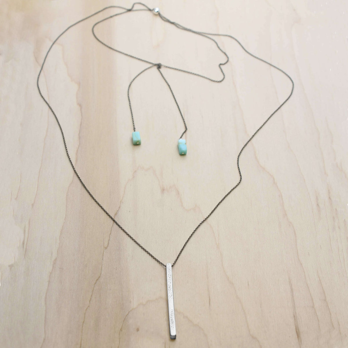 Twig Long Layered Necklace on a wooden background with adjustable chain and turquoise accents.