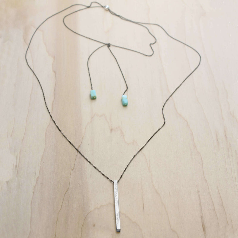 Twig Long Layered Necklace on a wooden background with adjustable chain and turquoise accents.